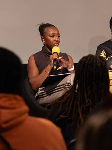 Our host, Stacey Olika, speaking into a microphone during the event.