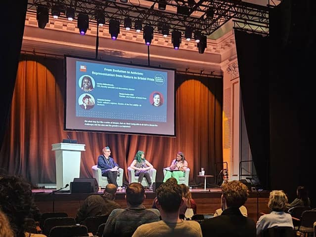 Three panellists seated on stage during the Bristol Distinguished Address Series talk ‘From Evolution to Activism’, with the presentation slide projected above them.