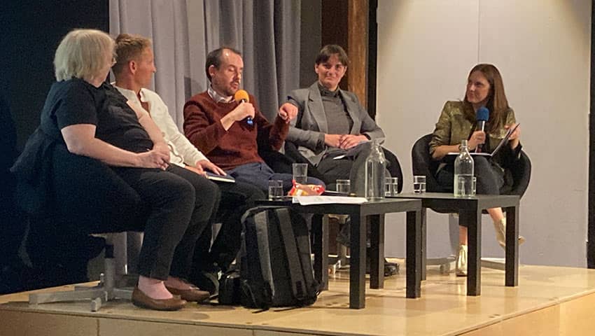 Photo of the event panel sitting on stage during the talk.