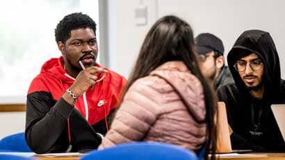 Student turning around to have a discussion with students behind within a classroom.