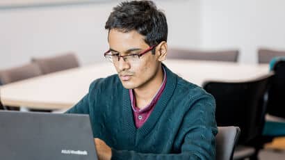 A business student writing a report on a laptop.