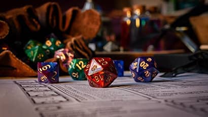 Close up of a role playing game table containing dice and character sheets.