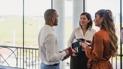 A group of professionals standing in a circle and chatting in an office space.