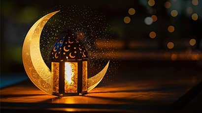 A lantern in front of a crescent moon shaped object at night.