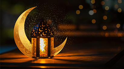A lantern in front of a crescent moon shaped object at night.