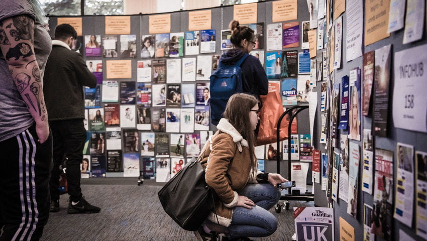 A female student looks at posters at the employers fair