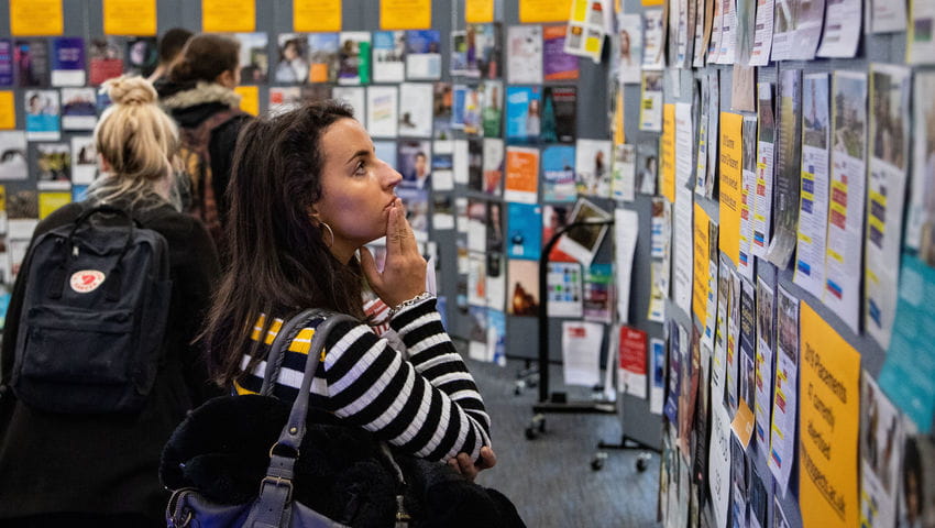 A student looks at posters at the employer fair