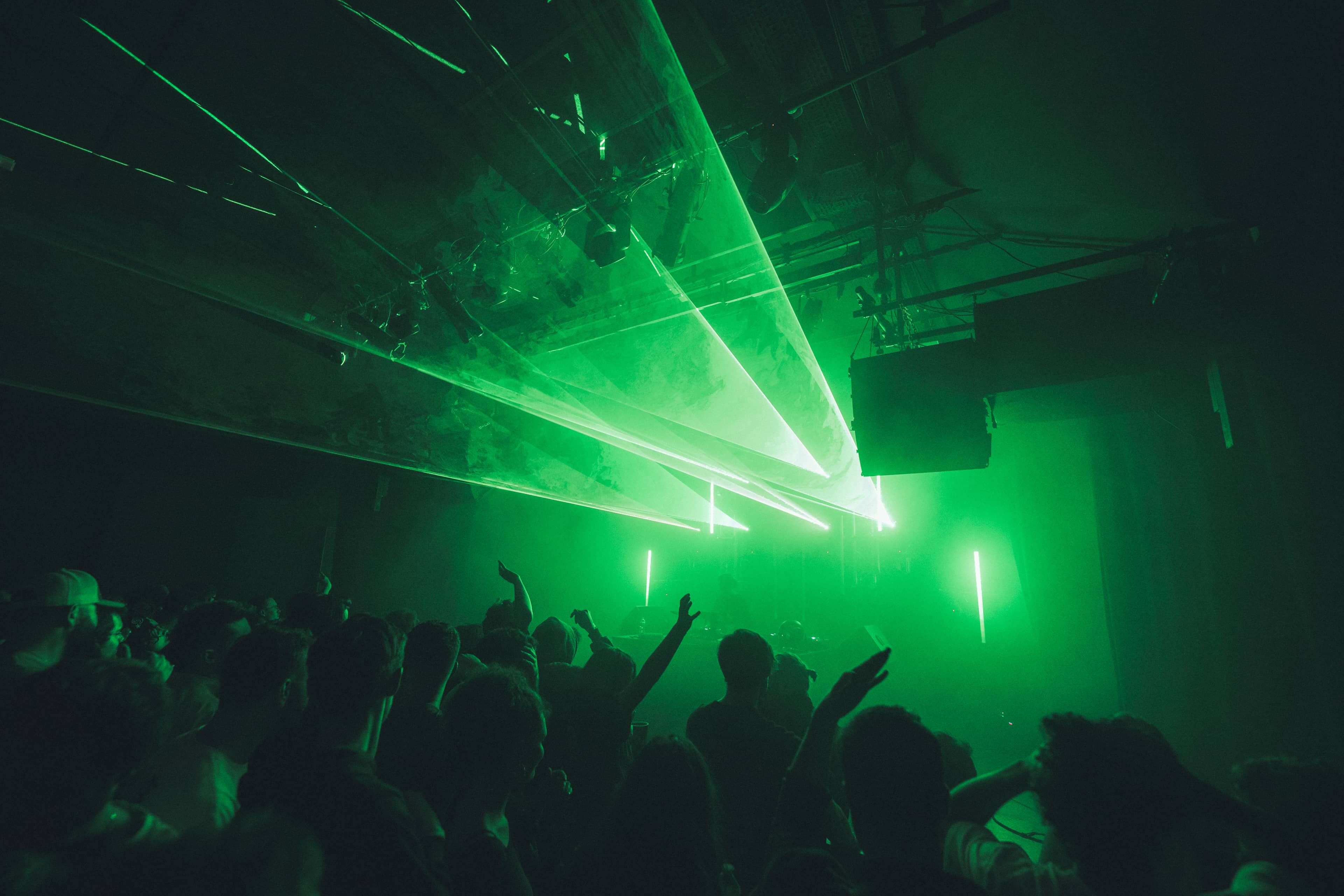 People dancing under a green strobe light at a basement rave.