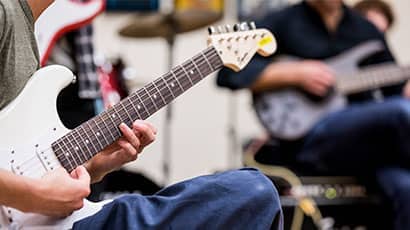 Someone attending a music lesson and playing an electric guitar.
