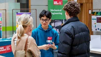 Student talking to a parent and young person at an open day.