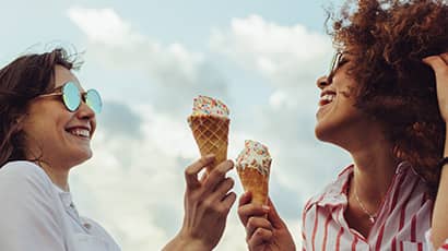 Two young women holding ice cream and smiling.