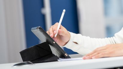 Close up of a student writing on a tablet