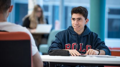 Student working in a study space talking to another student