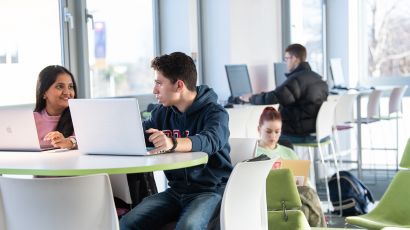 Two students in a classroom working on their laptops