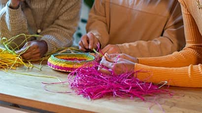 Three people weaving a basket