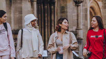 Four students walking around the city centre and talking to each other.