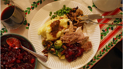 A Christmas meal with cranberry sauce, meat, mashed potatoes, brussel sprouts, and much more.