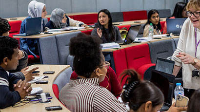 A group of students in a classroom talking to their lecturer