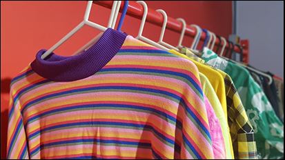 Colourful t-shirts hanged on hangers