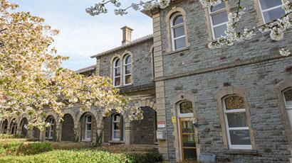 Outside view of Glenside Campus building with trees, blue sky and green grass