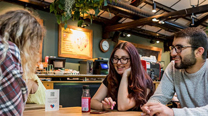 Three students talking to each other in a café