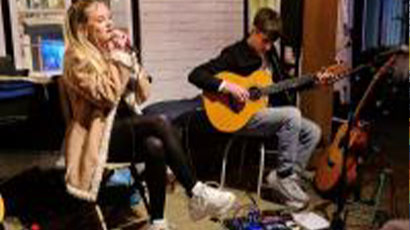 A female student singing and a male student playing the guitar
