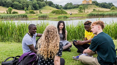 A group of students sitting on the grass in a park 