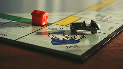 A close look of Monopoly board game with a mini car and a house toy