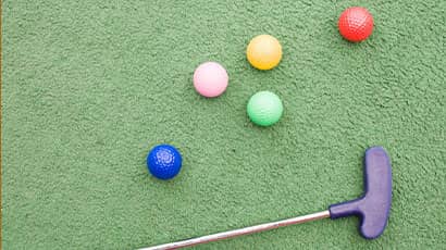 A golf club and balls on green grass