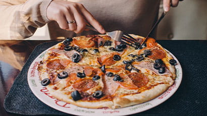 A person is cutting a pepperoni pizza