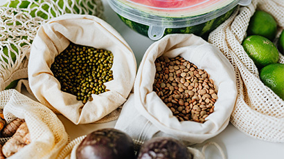 Different types of fruits, vegetables, and grain in small jute sacks.