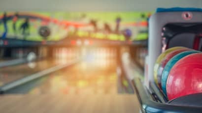 Colourful bowling balls stacked in a bowling alley.