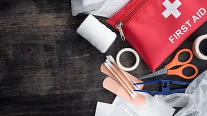 A selection of first aid materials including plasters, scissors, bandages and a first aid kit bag.