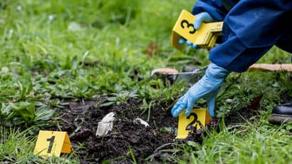 A forensic science student laying out coloured labels on the ground to indicate evidence.