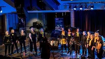Group of women singing around microphones