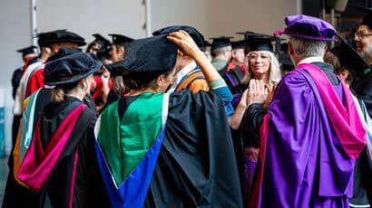 A group of academics adjusting their graduation robes.