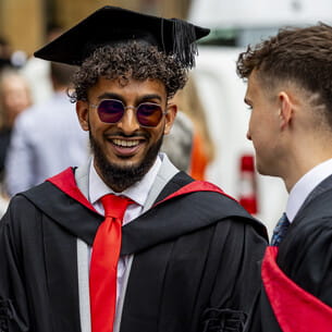 Two graduates in robes talking to each other.