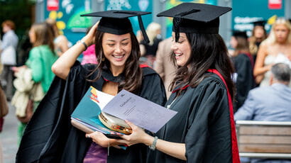 Two graduates walking outside a graduation venue