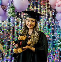 Graduate posing with teddy bear dressed in graduation robes