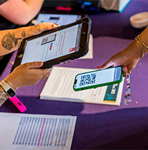 Scanning a QR code on a student's phone at the registration desk for graduation