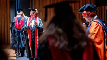 Graduate walking on stage being applauded by the vice-chancellor