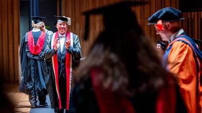 Graduate walking on stage being applauded by the vice-chancellor