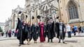 A group of graduates raising their caps outside Bristol Cathedral