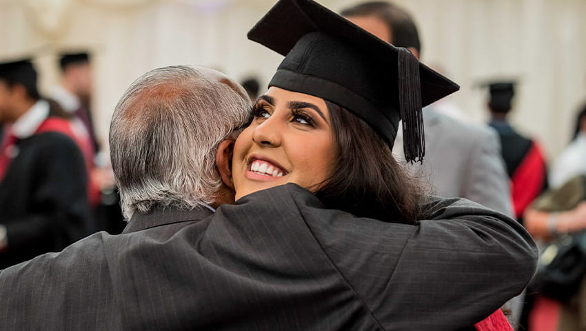 Graduate smiling and hugging relative