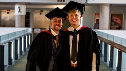 A pair of graduates posing wearing their graduation robes