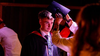 Graduate getting fitted for their graduation cap and gown