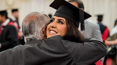 Graduate smiling and hugging a family member