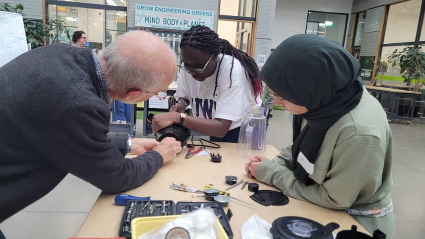 Students and a technician mending electronics in the Repair Café.