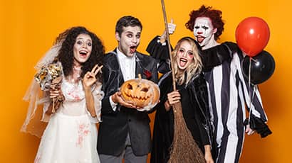 Four people in Halloween costumes of a spooky bride, spooky groom, witch and clown.