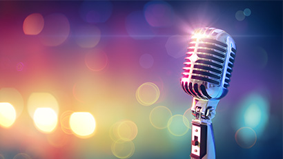 An old-fashioned microphone gleaming in the spotlight with colourful lights in the background.